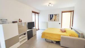 ein Schlafzimmer mit einem gelben Bett und einem TV in der Unterkunft Arcolovers in Arco