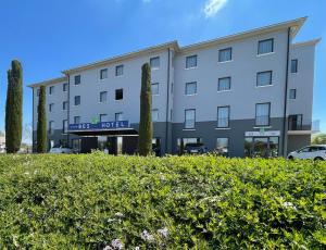 ein Hotel mit einer Hecke vor einem Gebäude in der Unterkunft Bes Hotel Cremona Soncino in Soncino