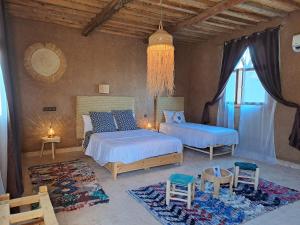 a bedroom with two beds and chairs and a window at Riad Dar Tiziri in Zagora