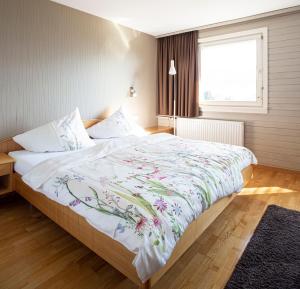 a bedroom with a large bed with a floral bedspread at Hotel Gasthof Wälderhof in Lingenau