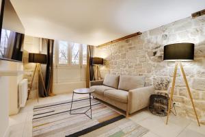 a living room with a couch and a stone wall at Pick A Flat's Apartment on l'Ile de la Cité - Quai de L'Horloge in Paris