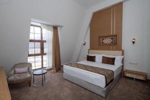 a bedroom with a bed and a chair and a window at Marxal Resort & Spa in Sheki