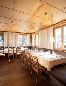 una sala da pranzo con tavoli, sedie e finestre di Hotel Gasthof Wälderhof a Lingenau
