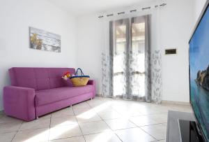 un sofá púrpura en una sala de estar con ventana en Bedda Luna Villa en San Vito lo Capo