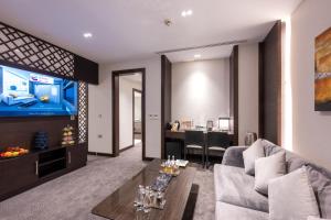 Ramada Encore Doha by Wyndham في الدوحة: غرفة معيشة مع أريكة وتلفزيون