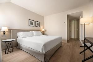 a bedroom with a large white bed and a desk at Exe Coruña in A Coruña