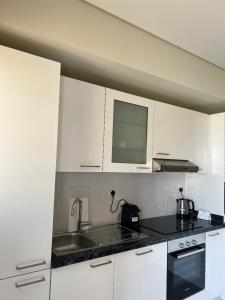 una cocina con armarios blancos y fregadero en Cozy new townhouse for 6 people!, en Salalah