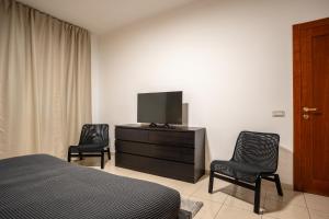 een slaapkamer met een bed en 2 stoelen en een televisie bij Home Abate Gimma 170 in Bari