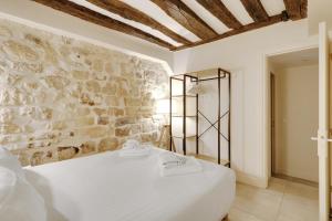 a white bed in a room with a stone wall at Pick A Flat's Apartment on l'Ile de la Cité - Quai de L'Horloge in Paris