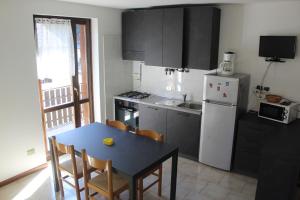 a kitchen with a table and a white refrigerator at Casa Pineta in Ledro