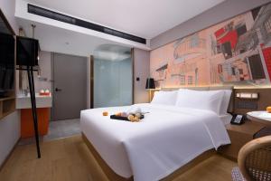 a bedroom with a large white bed and a television at From K Huan Kai Hotel -Changsha Wuyi Plaza IFS Branch in Changsha