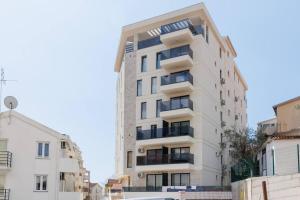 a tall white building with balconies on a street at SEASALT Apartments Rafailovichi in Budva