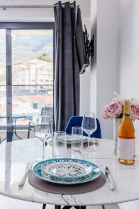 a table with a plate and wine glasses on it at SEASALT Apartments Rafailovichi in Budva +12 photos
