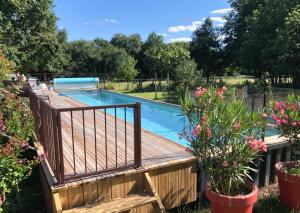 a wooden deck with a pool in a yard at Relais de La Brande in Saint-Gourson