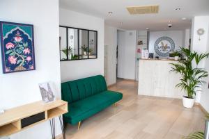 a living room with a green couch and a kitchen at Vitium Córdoba in Córdoba