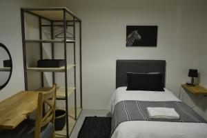 a bedroom with a bed and a desk and a shelf at Zebra Cottage - House - Backup Power - Fast WIFI in Pretoria