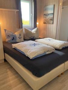 um quarto com 2 camas com almofadas e uma janela em Bootshus - Strandpark 15 em Grömitz
