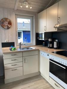 uma cozinha com armários brancos, um lavatório e uma janela em Bootshus - Strandpark 15 em Grömitz