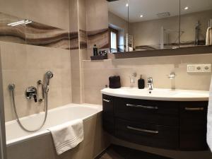 a bathroom with a tub and a sink and a shower at Evelyn – Haus Karwendel, Ferienwohnung in Mittenwald +45 photos
