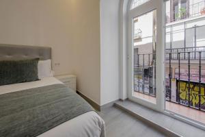 sypialnia z łóżkiem i dużym oknem w obiekcie SUARA Apartamentos 2 w Madrycie