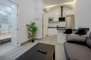 een woonkamer met een bank en een tafel en een keuken bij SUARA Apartamentos 2 in Madrid