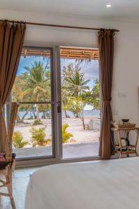 a bedroom with a view of the beach through a window at BeachWalk Koh Rong in Koh Rong Island