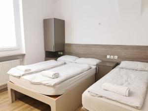Rooms Ambrožič في ليوبليانا: سريرين في غرفة مع ملاءات بيضاء ومناشف