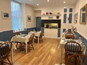 a dining room with tables and chairs and a kitchen at Awel Mor in Criccieth