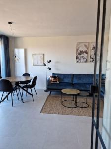 uma sala de estar com um sofá azul e mesas em Phoenix em Gent