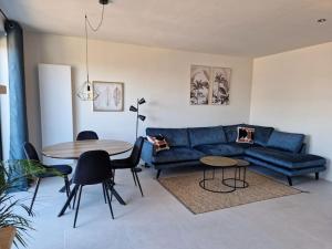 Phoenix في خنت: غرفة معيشة مع أريكة زرقاء وطاولة