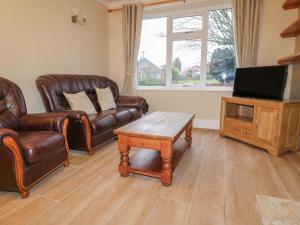 uma sala de estar com mobiliário de couro e uma televisão de ecrã plano em Cheriton em Tuxford