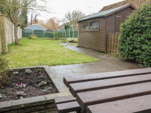 um jardim com um banco de madeira ao lado de um barracão em Cheriton em Tuxford