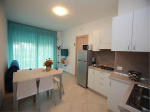 eine Küche mit weißen Schränken und einem Tisch mit weißen Stühlen in der Unterkunft Elegant apartment near the beach-Beahost Rentals in Rosolina Mare