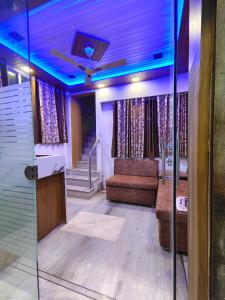 Habitación con sofá y techo con luces azules. en HOTEL ANJALI en Ujjain