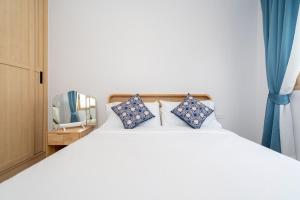 una camera da letto con un letto bianco con cuscini blu di Brand New 2BR House in Yamu Garden A1 a Ban Bang La