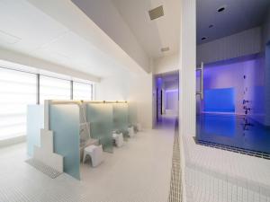 baño con una fila de urinarios y aseos en GINZA HOTEL by GRANBELL, en Tokio