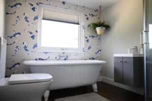baño con bañera blanca y papel pintado azul en The Coach House at Wenvoe Manor, Cardiff, en Wenvoe