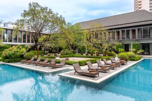 Villa Deva Resort & Hotel Bangkok في بانكوك: مسبح وكراسي صالة ومبنى