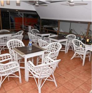 um grupo de mesas e cadeiras brancas num restaurante em Coco homes by myroom em Candolim