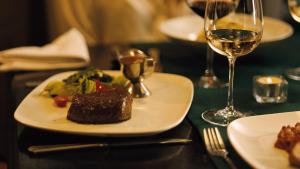 einen Teller mit Essen auf einem Tisch mit einem Glas Wein in der Unterkunft Hotel MERTIN in Chomutov