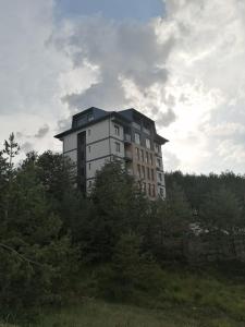 a tall building on top of a hill with trees at Apartman Ekvilibrijum in Zlatibor