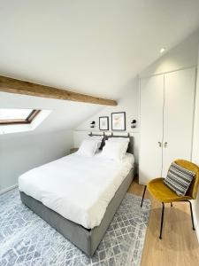 a bedroom with a large bed and a chair at Les Appartements de l'Orangerie in Versailles