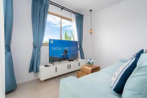 een woonkamer met een blauwe bank en een tv bij Newly Designed 3BR Fusion House in Yamu Garden B1 in Ban Bang La
