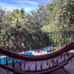 a hammock in a resort with a pool and trees at Cosy apartment with private swimming pool in Santa Cristina d'Aro