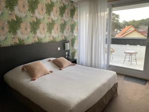 ein Schlafzimmer mit einem Bett und ein großes Fenster mit einer Terrasse in der Unterkunft Le Regina Hôtel restaurant in Hardelot-Plage