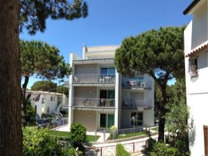 un immeuble d'appartements avec des arbres au premier plan dans l'établissement Charming flat for up to 6 guests near the beach, à Rosolina Mare