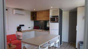 cocina con mesa blanca y silla roja en CAMPING MONTE ORTU en Lumio