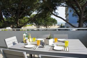 リド・ディ・イエゾロにあるAppartamenti Aquamarinaの白いテーブル、椅子、バルコニー(ドリンク付)