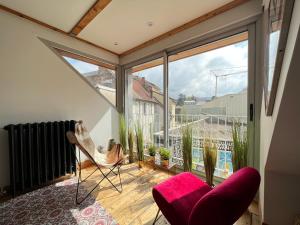 een kamer met een balkon met een stoel en een raam bij Pépite au plein centre historique in Lons-le-Saunier