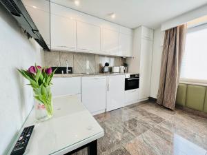 una cocina con armarios blancos y un jarrón de flores en un mostrador en North Nest Luxury Suites en Gdansk